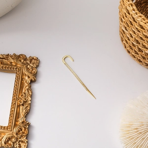 Macro view of a minimalist golden U-shaped ear cuff with a sleek cone-shaped metal handle