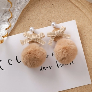 Vue détaillée des boucles d'oreilles nœud kaki avec pompons en fourrure et bois