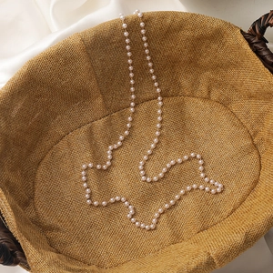 Macro shot of elegant white pearl and gold bead eyewear strap on woven texture