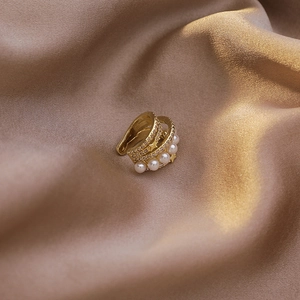 Détail du bijou d'oreille doré multi-couches avec perles, zircons et accents d'étoile