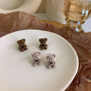 Detail of flocking bear stud earrings with bow tie in dark brown and beige colors