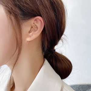 Detail of gold metal wire ear cuff in a minimalist love script font worn on ear