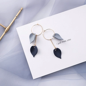 Macro shot of gold hoop earrings with matte blue and grey leaf pendants on soft mesh