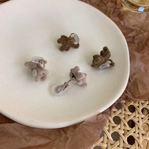 Close-up of cute flocked bear earrings with velvet texture in a ceramic bowl