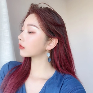 Close-up of model wearing blue leaf drop earrings with a matte finish and hook design