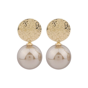 Vue détaillée de clous d'oreilles en métal martelé avec perles couleur champagne