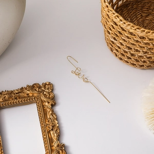 Detail of elegant gold Love letter earring with polished finish on a minimalist background