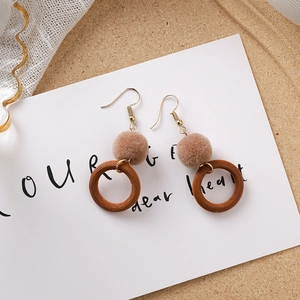 Détail de boucles d'oreilles d'automne avec pompons en peluche kaki et cercles en bois