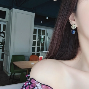 Detailed close-up of blue resin hoop earrings with hammered gold metal worn by a model