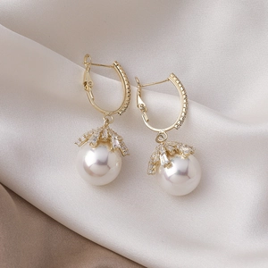 Detailed close-up of gold-plated French U-shaped earrings with pearls and pavé zircons