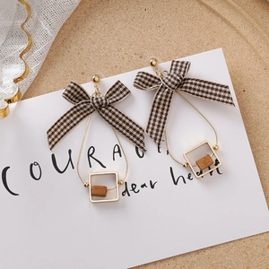 Détail des boucles d'oreilles nœud pied-de-poule avec métal doré et perles de bois marron