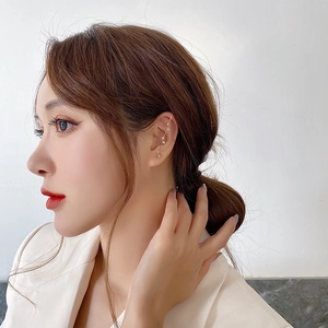 Detailed close-up of golden ear cuff with sparkling zircons on a female model
