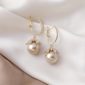 Detailed macro view of champagne pearl drop earrings with gold pavé crystal ear hooks