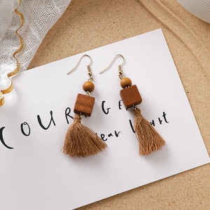 Vue détaillée de boucles d'oreilles bohèmes en perles de bois brun et glands de coton
