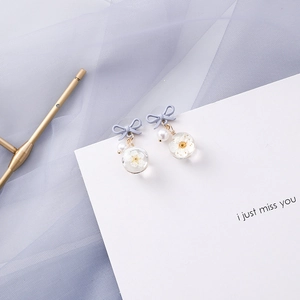 Detailed view of handmade flower resin earrings with purple bows and pearl accents
