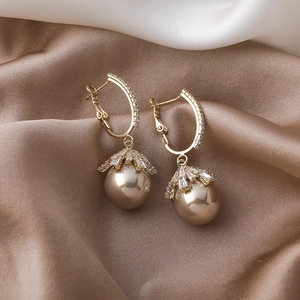 Close-up of champagne pearl drop earrings with gold hoops and sparkling cubic zirconia