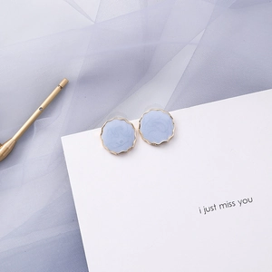 Detail of blue-grey round earrings with wavy gold edges and marble texture