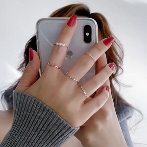 Five-piece rose gold ring set with minimalist bands and faux pearls on fingers