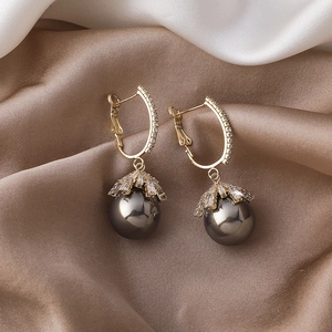 Detailed view of champagne gold pearl earrings with zircon inlay on silk background