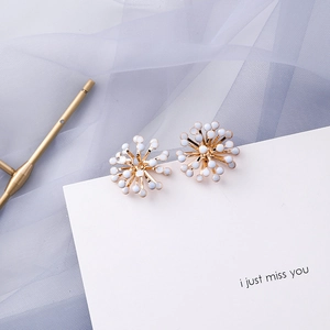 Detail of golden sunburst stud earrings with white pearl accents on display card