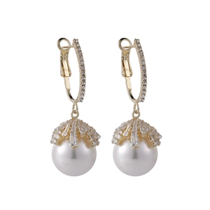 Detailed macro of vintage style white pearl earrings with 18k gold zircon u-shaped hooks