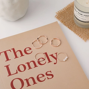 Detailed view of a 5-piece rose gold ring set with pearls on a book surface