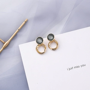 Detail of blue-grey geometric drop earrings with gold circles on white card