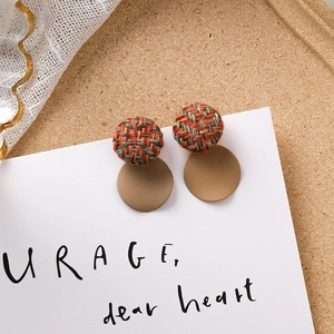 Détail de boucles d'oreilles en tweed marron et acrylique sur carte esthétique