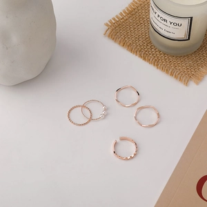Detailed view of five-piece rose gold ring set featuring minimalist bands and pearls