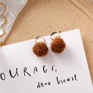 Détail de boucles d'oreilles vintage avec pompon marron et disque doré texturé