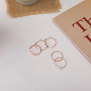 Detail view of five-piece rose gold minimalist ring set with elegant pearl accents