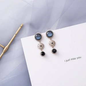 Close-up of vintage geometric earrings with blue gemstones and sunflower metal detail