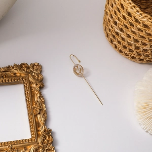 Close-up of golden smiley face earring with sparkling cubic zirconia on a vintage frame