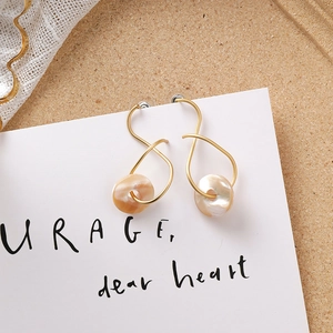 Vue macro détaillée des boucles d'oreilles dorées en S avec perles nacrées