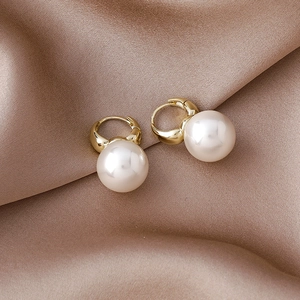 Elegant gold huggie hoop earrings with large white pearls on champagne silk fabric