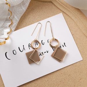 Détail de boucles d'oreilles géométriques en résine marron avec anneaux dorés superposés