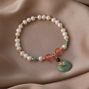 Elegantes Süßwasserperlenarmband mit grünem Jade-Anhänger auf braunem Seidenstoff