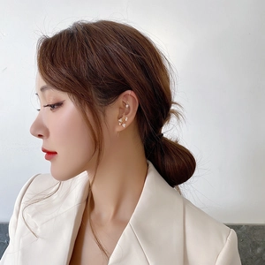 Detailed close-up of an elegant golden ear cuff featuring delicate white cluster pearls