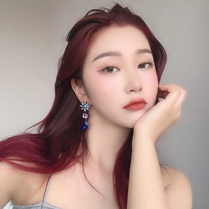 Close-up of geometric drop earrings with blue and purple gems worn by a female model