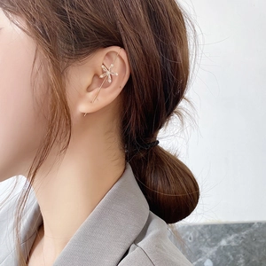 Detail of gold star-shaped zircon ear crawler earring worn by a model in a modern style