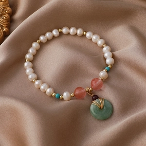 Elegantes Süßwasserperlen-Armband mit grünem Jade-Anhänger auf Seidenhintergrund