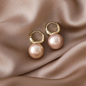 Detail of luxury champagne pearl earrings on elegant silk fabric background