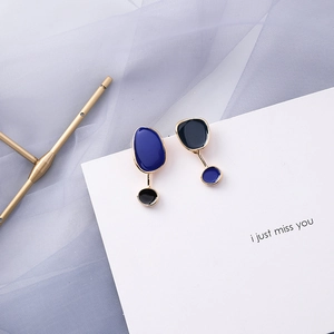 Detailed view of asymmetrical geometric earrings with dark blue and black enamel details