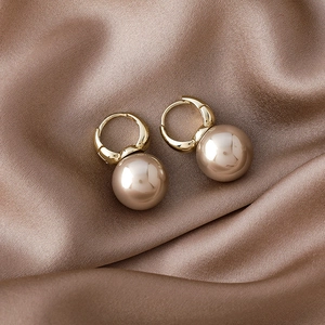 Detail of luxury champagne pearl hoop earrings on soft coffee silk fabric background