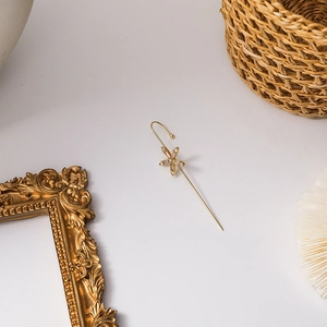 Close-up of golden floral ear cuff with sparkling crystals on a vintage background