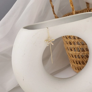 Detailed macro view of gold floral ear wire earrings with white zircons on ceramic