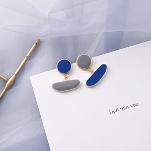 Detail of blue and gray geometric drop earrings with gold trim on decorative card
