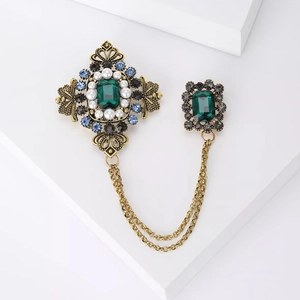 Broche vintage avec strass vert émeraude, chaîne à glands et perles sur base dorée