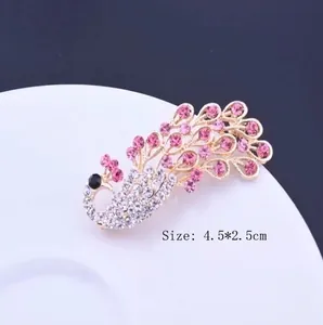 Elegant peacock brooch pin with sparkling pink and white crystals on a gold base