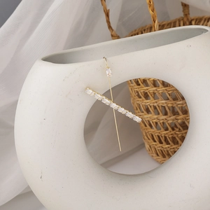 Detail view of gold geometric ear crawler with rectangular crystals on a white ceramic vase